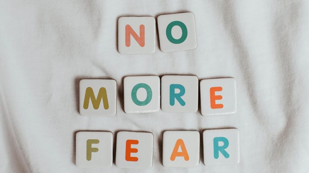 Colorful letter tiles spelling 'No More Fear' placed on a soft white fabric background.